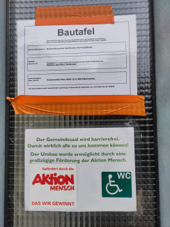 Bild der Bautafel und einem Hinweis auf Barrierefreiheit und die Aktion Mensch